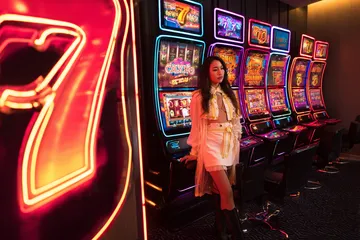 A stylish woman beside vibrant slot machines displaying glowing sevens, showcasing the variety of top slots at SPINARA.