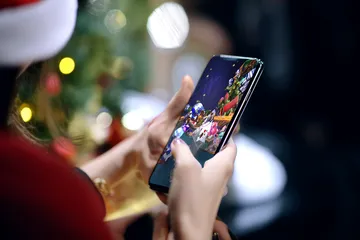 A player using their smartphone during a festive local event, representing SPINARA’s fully mobile-friendly casino.